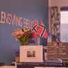 Skranken på Odda bibliotek er pyntet med en bukett i en vase, tre norske flagg, tre av Jon Fosses bøker utsilt samt et bilde av Jon Fosse. Foto.